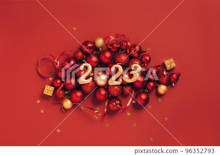 Date 2023 red background of Christmas toys, balls sparkles. Beautiful festive New Year's mockup 96352793