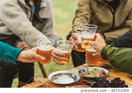 Hands of men and women who drink beer and party with friends at a campsite in autumn and winter Hands of men and women who drink beer and party with friends at a campsite in autumn and winter 96353004