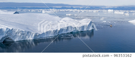 Climate Change and Global Warming. Icebergs from melting glacier in Ilulissat, Greenland with boat for showing immense scale. Arctic nature landscape affected by global warming. Sustainability concept Climate Change and Global Warming. Icebergs from melting glacier in Ilulissat, Greenland with boat for showing immense scale. Arctic nature landscape affected by global warming. Sustainability concept 96353162