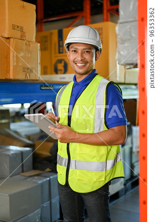 Handsome Asian warehouse worker smiling, looking at camera while working in warehouse. Handsome Asian warehouse worker smiling, looking at camera while working in warehouse. 96353362