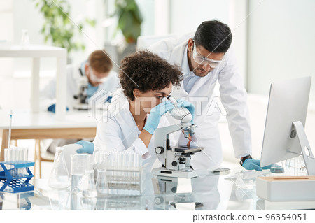 female scientist and her colleague using a microscope in the laboratory. female scientist and her colleague using a microscope in the laboratory. 96354051