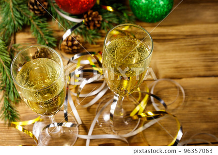 Two glasses of champagne and festive Christmas decorations on wooden table. Christmas and New Year celebration Two glasses of champagne and festive Christmas decorations on wooden table. Christmas and New Year celebration 96357063