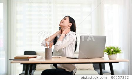 Overworked Asian businesswoman suffering from neck pain after had a long day at work 96357252