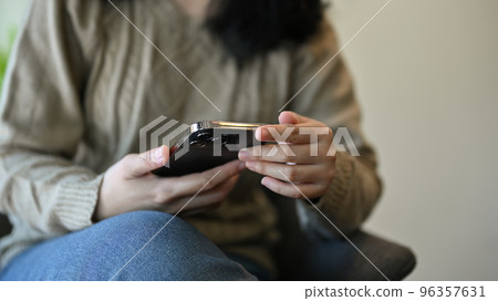 cropped, An Asian female in sweater using her mobile phone to text to her friends 96357631