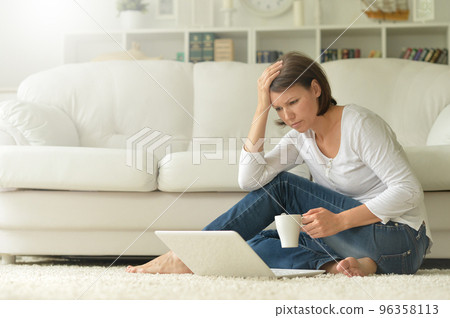 Portrait of a beautiful woman with a laptop on the floor 96358113