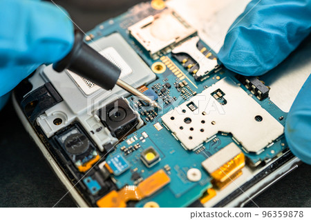 Technician repairing inside of mobile phone by soldering iron. Integrated Circuit. the concept of data, hardware, technology. 96359878
