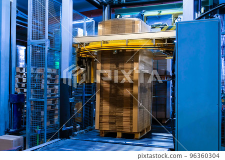 Industrial equipment - typical stretch wrapping machine in process of work. Packaging of corrugated cardboard. Selective focus. Industrial equipment - typical stretch wrapping machine in process of work. Packaging of corrugated cardboard. Selective focus. 96360304