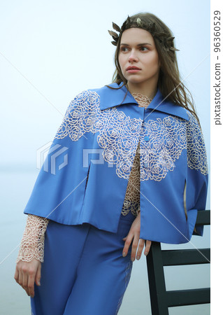 Fashion model leaning against a chair in a cloudy day on a beach Fashion model leaning against a chair in a cloudy day on a beach 96360529