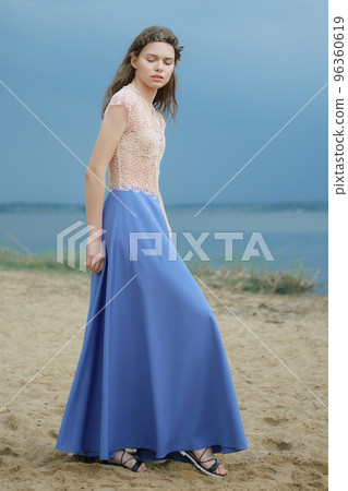 Dreamy woman in long blue skirt and lace blouse on the beach 96360619