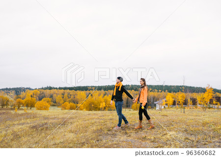 A couple in love holds hands and walks through an autumn garden or field. Enjoy the autumn nature and each other A couple in love holds hands and walks through an autumn garden or field. Enjoy the autumn nature and each other 96360682