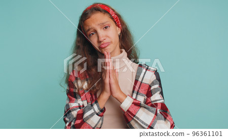 Child girl kid sincerely praying to God and looking up with pleading expression, begging apology 96361101