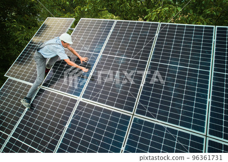 Aerial view of man technician installing photovoltaic solar panels to high steel platform. Concept of alternative energy. Aerial view of man technician installing photovoltaic solar panels to high steel platform. Concept of alternative energy. 96361731