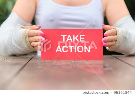 A girl with two hands in a cast holds a card with the inscription TAKE ACTION. ACTION PLAN in a difficult situation. Strategic Vision Planning. 96361844