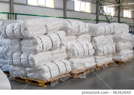 Large white bags with finished products are stacked on pallets and are in the warehouse. Large white bags with finished products are stacked on pallets and are in the warehouse. 96362640