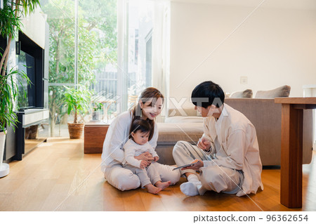 Parents reading a picture book to their baby Parents reading a picture book to their baby 96362654