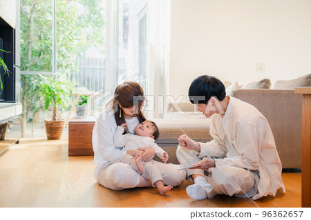 Parents reading a picture book to their baby Parents reading a picture book to their baby 96362657