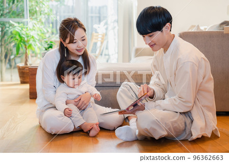 Parents reading a picture book to their baby Parents reading a picture book to their baby 96362663