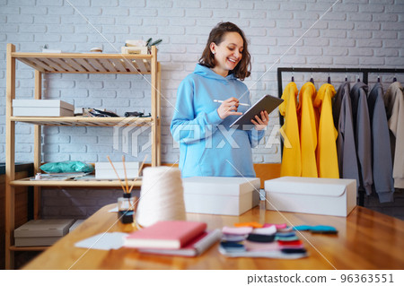 Small business owner, entrepreneur, seller using tablet checking ecommerce clothing store orders. 96363551