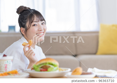 作弊日一個年輕女子手裡拿著一個甜甜圈微笑 作弊日一個年輕女子手裡拿著一個甜甜圈微笑 96363710
