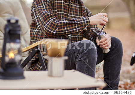 A young man enjoying coffee at a campsite. A young man enjoying coffee at a campsite. 96364485