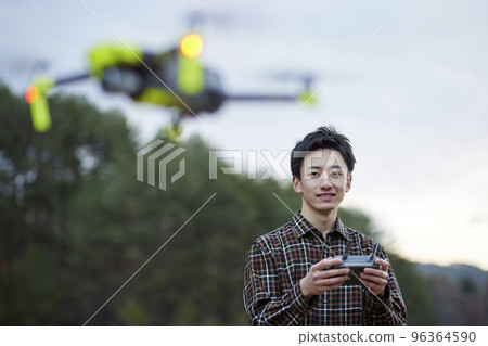 Young Japanese man piloting a drone Young Japanese man piloting a drone 96364590