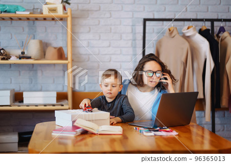 Young mother works with little boy. Business Woman talking on the phone and discussing work issues. Young mother works with little boy. Business Woman talking on the phone and discussing work issues. 96365013