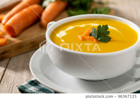 Carrot soup with cream and parsley on wooden table. 96367135