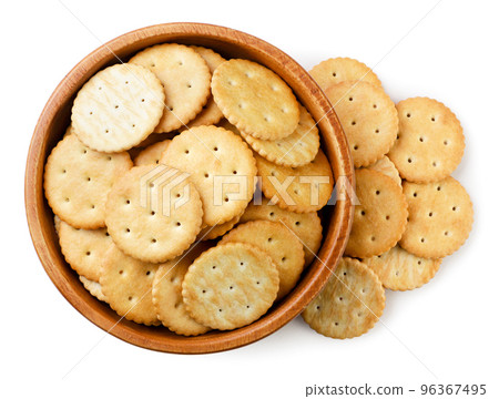 Crackers in a wooden plate and scattered on a white background. top view 96367495
