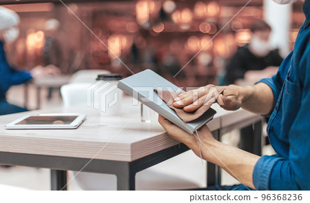 man in a protective mask processing personal belongings with antiseptic man in a protective mask processing personal belongings with antiseptic 96368236
