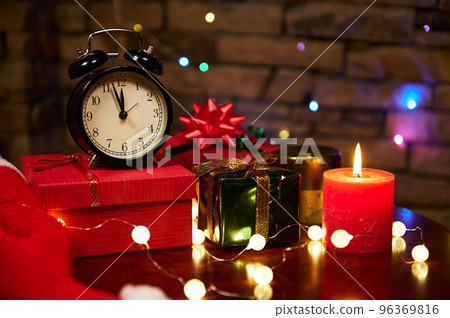 Christmas background with black alarm clock with midnight on face clock, candlelight. Happy New Year Christmas background with black alarm clock with midnight on face clock, candlelight. Happy New Year 96369816