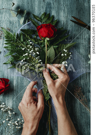 man is arranging a bouquet with red roses man is arranging a bouquet with red roses 96370185