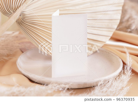 Folded card near dried palm leaf and beige silky fabric close up, greeting or wedding mockup Folded card near dried palm leaf and beige silky fabric close up, greeting or wedding mockup 96370935