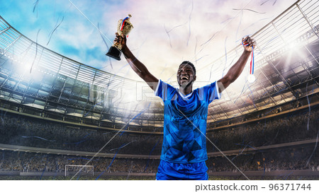 Soccer player in blue uniform rejoices for the victory of a trophy at the stadium Soccer player in blue uniform rejoices for the victory of a trophy at the stadium 96371744