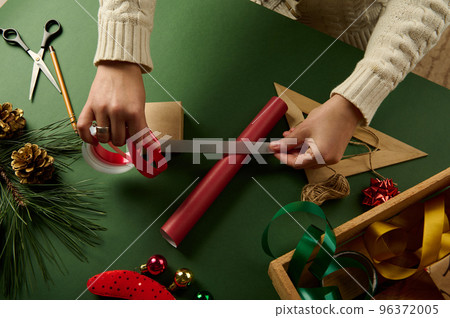 Top view hands hold white ribbon over red wrapping paper Packing Christmas and New Year gifts. Boxing day. December 25th Top view hands hold white ribbon over red wrapping paper Packing Christmas and New Year gifts. Boxing day. December 25th 96372005