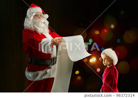 Santa Claus searches from a list a gift for a child 96372314