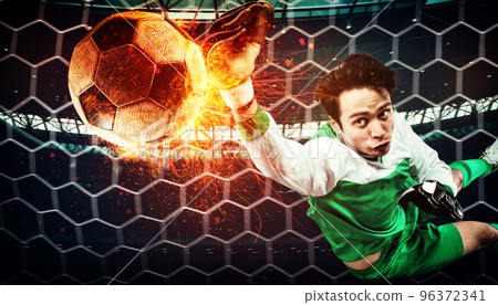 Close up of a soccer scene at night match with a goalkeeper trying to catch a fiery ball 96372341