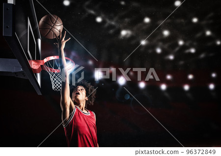 Basketball player in red uniform jumping high to make a slam dunk to the basket 96372849