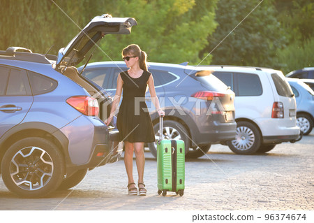 Young female driver loading luggage suitcase bag inside her car. Travelling and vacations concept 96374674