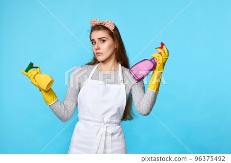 woman in rubber gloves chooses between two cleaning products woman in rubber gloves chooses between two cleaning products 96375492
