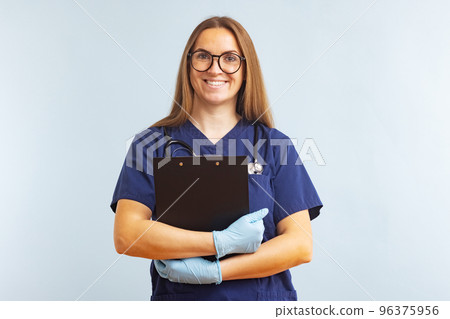 Female nurse or doctor with clipboard against a blue background Female nurse or doctor with clipboard against a blue background 96375956