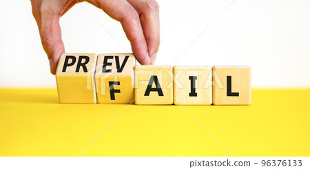 Prevail or fail symbol. Concept words Prevail or Fail on wooden cubes. Businessman hand. Beautiful yellow table white background. Business prevail or fail concept. Copy space. 96376133