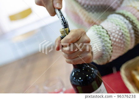 Corkscrew. Came. Time to open the bottle of red wine with the corkscrew. Woman's hands holding the bottle while opening the cork. Horizontal photography. Corkscrew. Came. Time to open the bottle of red wine with the corkscrew. Woman's hands holding the bottle while opening the cork. Horizontal photography. 96376238