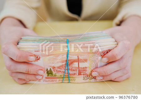 women's hands hold a stack of rubles tied with a rubber band. 96376780