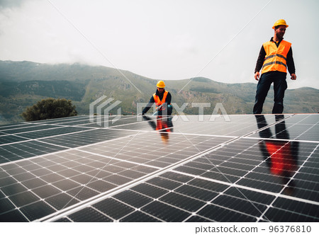 Workers assemble energy system with solar panel for electricity Workers assemble energy system with solar panel for electricity 96376810