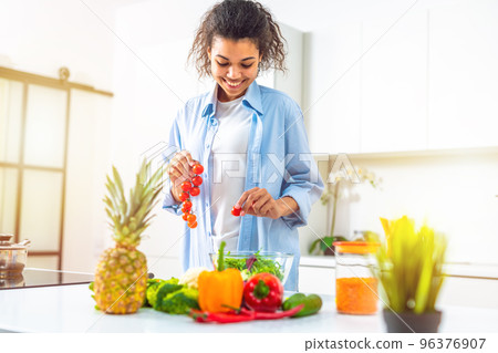 Young woman in the home kitchen prepares a genuine salad with fresh vegetables 96376907