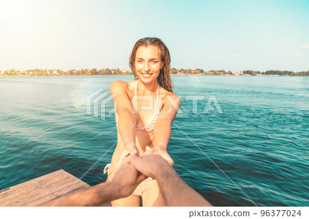 Point of view of a young woman in a swimsuit having fun with her partner at the sea 96377024