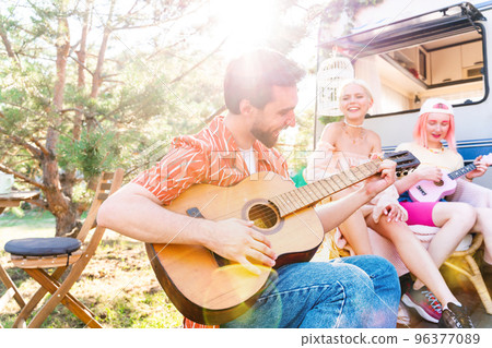 Friends have a picnic with a camper and play with guitar Friends have a picnic with a camper and play with guitar 96377089