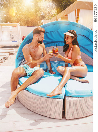 Couple in swimsuit drink a cocktail in a beach place Couple in swimsuit drink a cocktail in a beach place 96377129