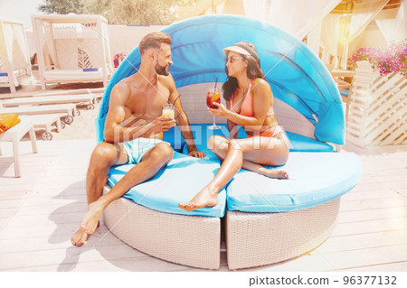 Couple in swimsuit drink a cocktail in a beach place Couple in swimsuit drink a cocktail in a beach place 96377132