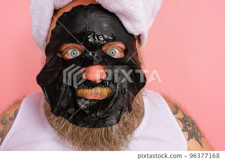 Doubter man with beard acts like a woman and has fun with a facial mask Doubter man with beard acts like a woman and has fun with a facial mask 96377168